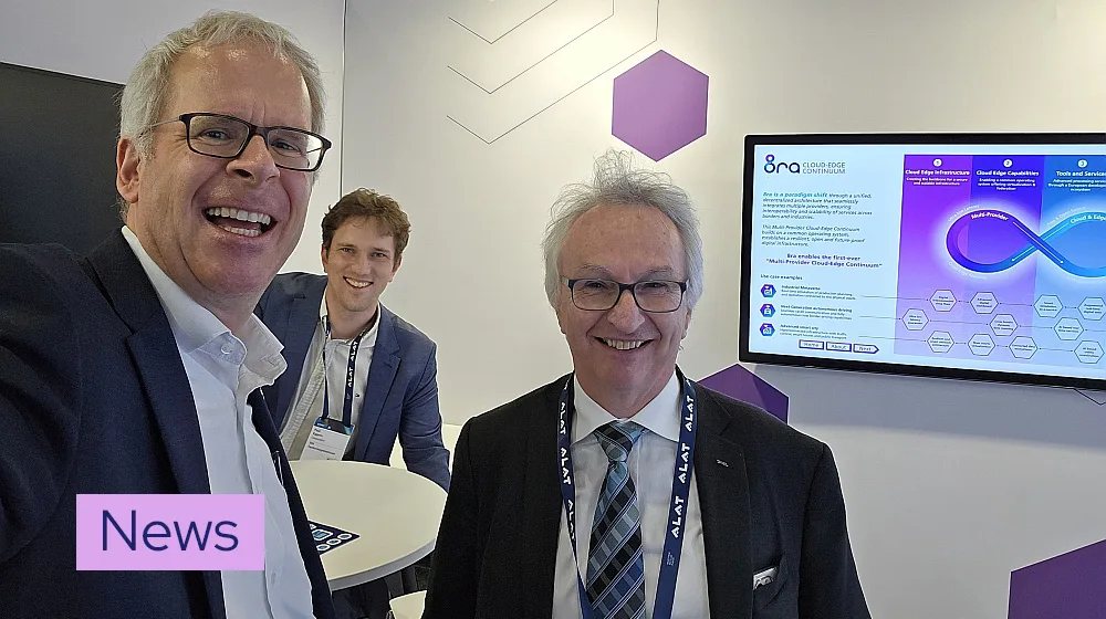 three smiling men at 8ra booth at Mobile World Congress 2025